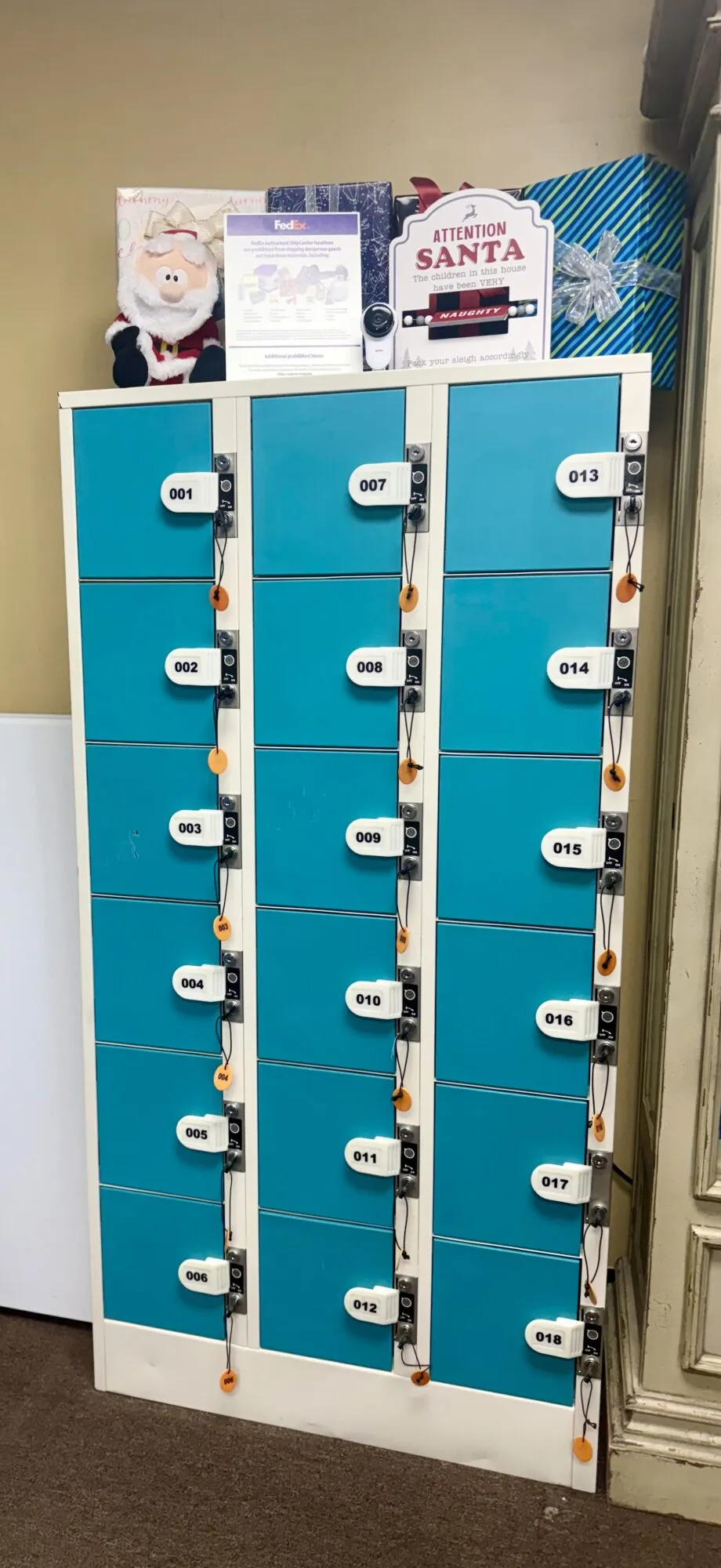 Blue package pickup lockers with packages and a shipping notice inside Mail World Office in Tulsa